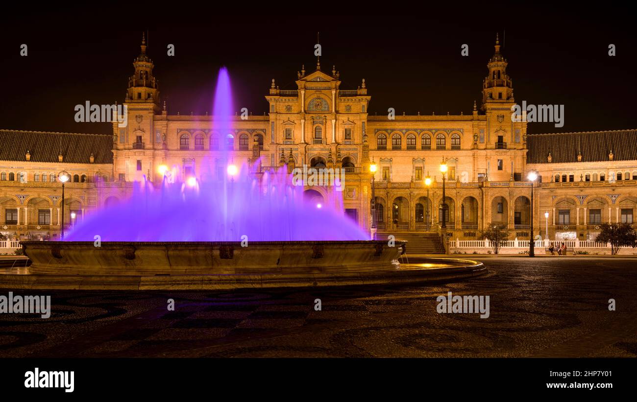 Purple Fountain - Ein Weitwinkel-Nachtansicht des beleuchteten Wasserbrunnens im Zentrum des spanischen Platzes - Plaza de España, Sevilla, Andalusien, Spanien. Stockfoto