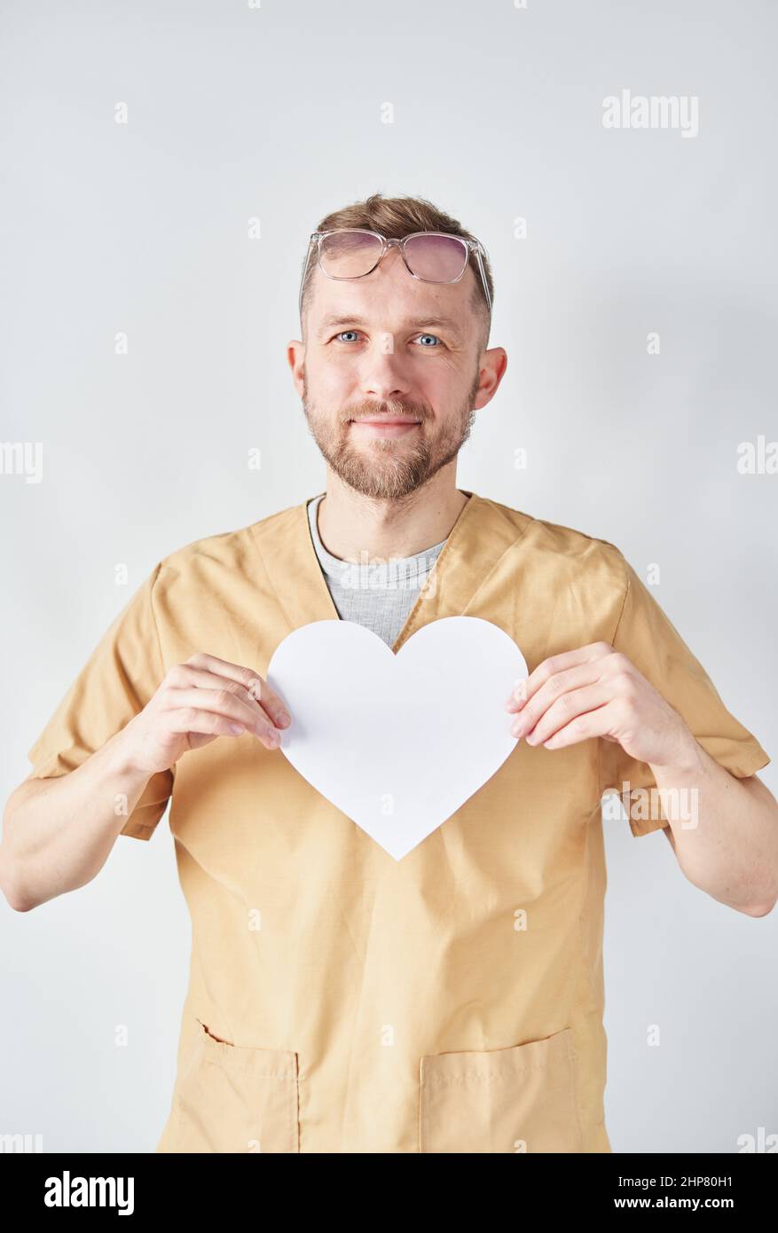 Porträt eines professionellen kaukasischen Arztes oder einer Krankenschwester, die eine Brille mit weißem Papier in Herzform trägt. Medizin und Gesundheitswesen oder National Doctor's Day Konzept. Hochwertige vertikale Fotos Stockfoto