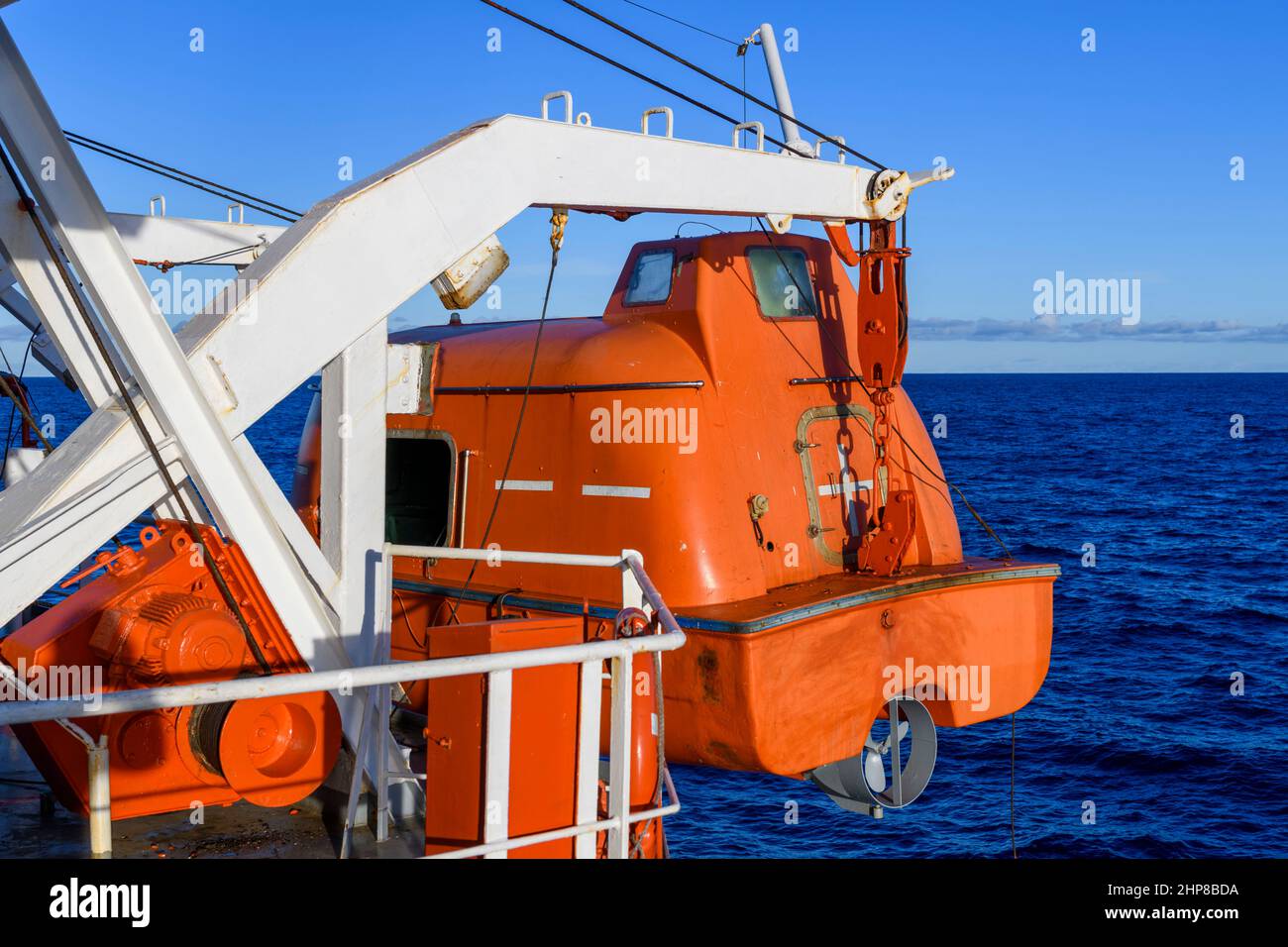 Das orangefarbene total umschlossene Rettungsboot zum Wasser absenken. Beenden Sie den Bohrer. Rettungsboot-Training. Mann über Bord Bohrer. Stockfoto