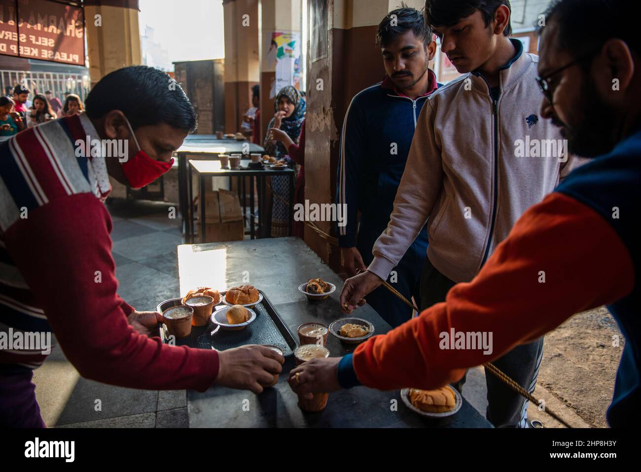 Lucknow, Indien. 18th. Februar 2022. Studenten, die Kulhad-Tee und Snacks am Sharma-Tee-Stand in Hazratganj, Lucknow, Indien, genießen.Teeliebhaber in Hazratganj, einer der ältesten Gegenden in Lucknow, der Hauptstadt von Uttar Pradesh, Wir genossen ihren ersten Schluck Morgentee an den beliebten Ständen, an denen den Besuchern Tee und Snacks serviert wurden. Touristen aus verschiedenen Orten und Lokalitäten kommen hier für einen frühen Morgenspaziergang und genießen den authentischsten Geschmack und Geschmack von Tee. Kredit: SOPA Images Limited/Alamy Live Nachrichten Stockfoto