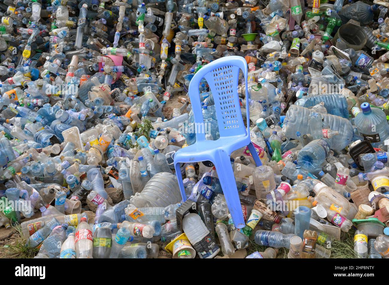 KENIA, Nairobi, Kibera Slum, Plastikflaschen von Nestle, Pepsico, Coca Cola and Co., Dumping, Getränkehersteller ersetzen Mehrwegglasflaschen mehr und mehr durch Einwegglasflaschen, aufgrund fehlender Recyclingsysteme wachsen und wachsen die Abfallberge, in der Mitte ein Plastikstuhl Monobloc / KENIA, Nairobi, Kibera Slum, Plastikflaschen von Coca Cola und Co, Coca Cola reduziert in Afrika die Glaspfandflaschen zunehmend und steigt dafür mehr auf den Verkauf von Einwegflaschen aus Plastik um, die Müllberge wachsen, Recycling Systeme fehlen, dazwischen ein Plastikstuhl Monobloc Stockfoto