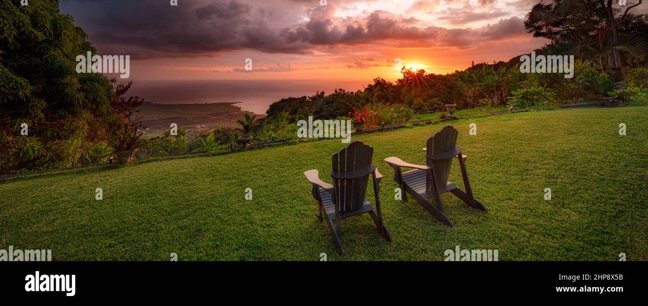 Blick auf den Sonnenuntergang und die Küste mit Stühlen. Hawaii, Die Große Insel. Stockfoto