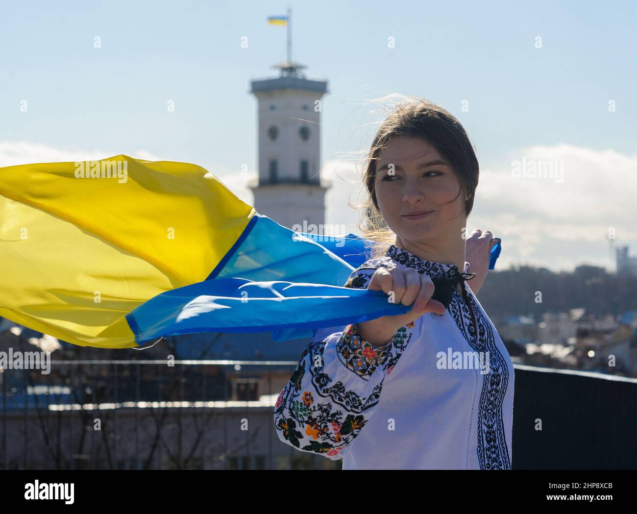Lviv, Ukraine, 19. februar 2022. Ukrainische Frau in besticktem Hemd hält ukrainische Flagge, nimmt an dem Einheits-Marsch für die Ukraine in der Innenstadt von Lemberg Teil, inmitten der Spannungen an der Ukraine-Russland-Grenze. Stockfoto