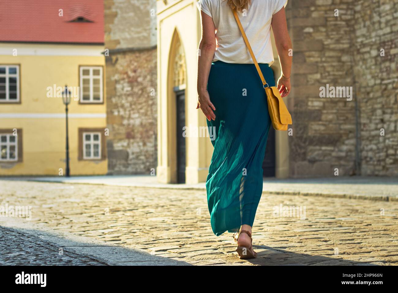 Frau in Faltenrock und Spaziergang in der Altstadt. Stilvolle Frau genießen Sommerurlaub in der europäischen Stadt. Stockfoto
