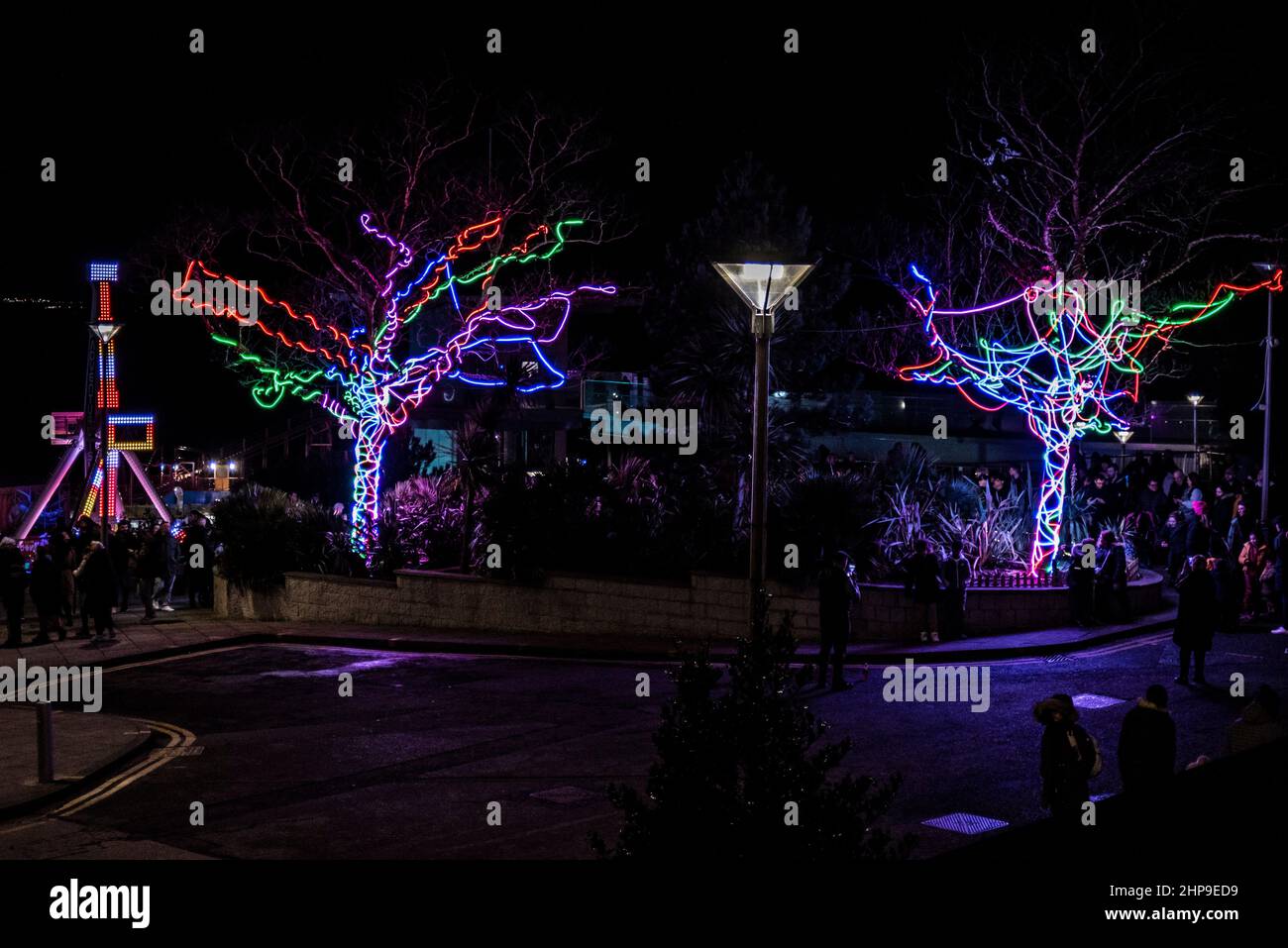 Beleuchtete Kunstinstallation im Rahmen der LuminoCity Temporary Structures Veranstaltung in Southend on Sea. Scribble Trees und Adventure Island Axis Ride Stockfoto