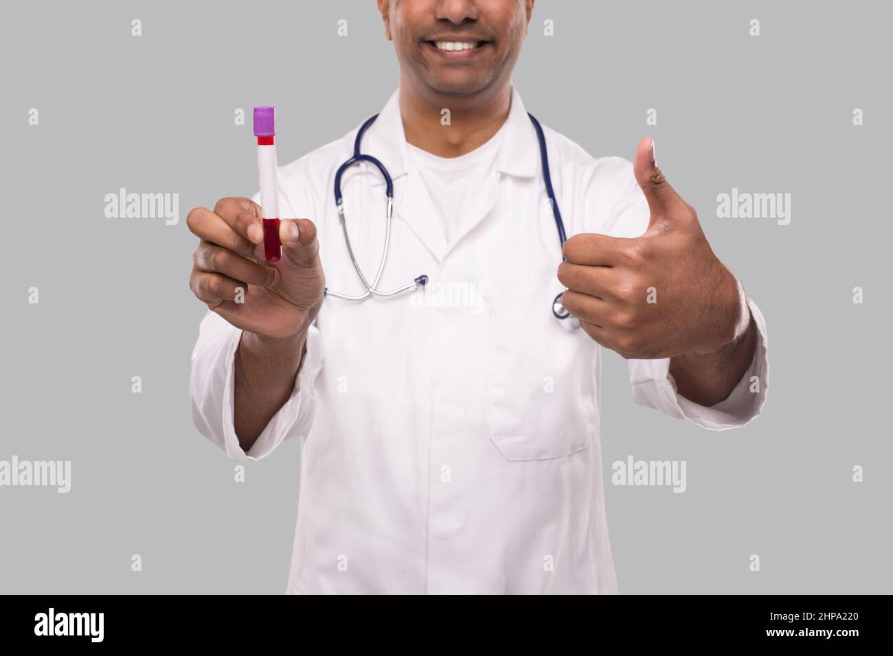 Indian Man Doctor Holding Blood Tube Analyse Zeigen Daumen Nach Oben Isoliert Nahaufnahme. Medizin, Wissenschaftskonzept Stockfoto