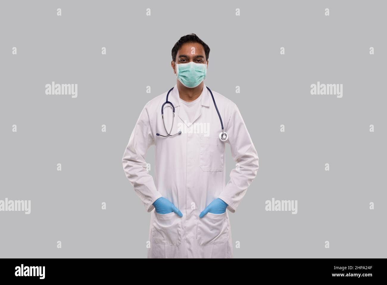 Arzt trägt medizinische Maske und Handschuhe stehen isoliert. Indischer Mann Arzt Medizinische Arbeitskleidung. Medizinisches Konzept Stockfoto