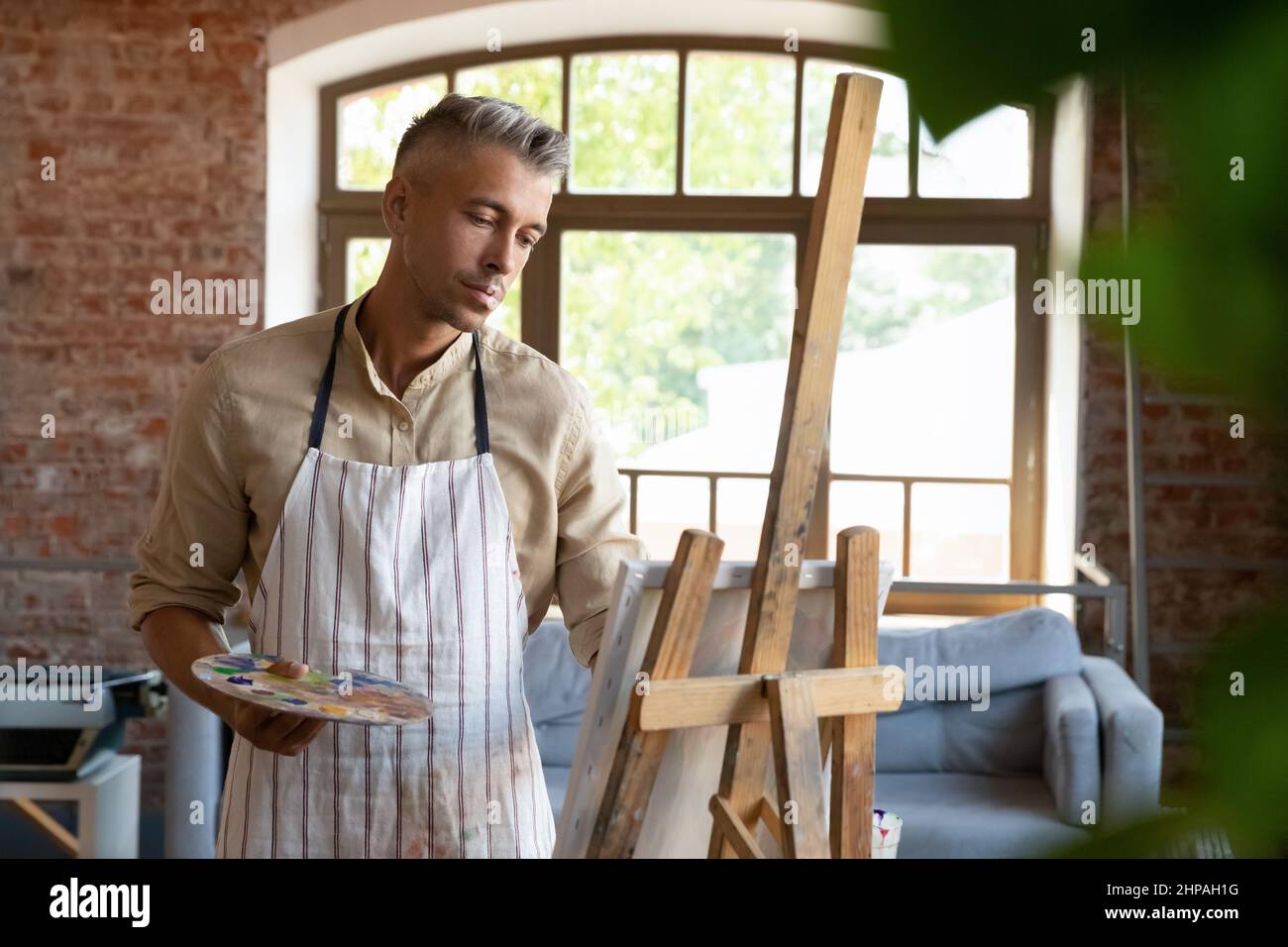 Entspannte glückliche 40s Mann Malerei im Kunststudio. Stockfoto