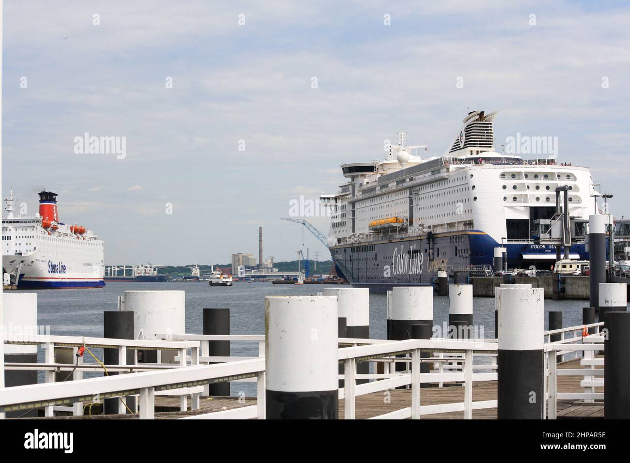 Blick auf das große Passagier-Freizeitschiff, das am Fährterminal im Kieler Hafen angedockt ist, mit Wolken im blauen Sommerhimmel im Hintergrund. Keine Personen. Stockfoto