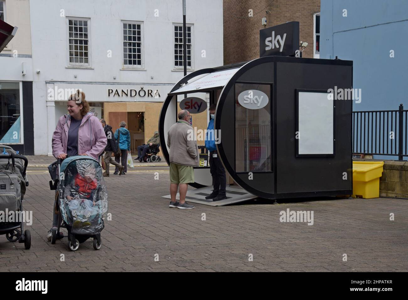 Ein Fußgänger hält an, um mit einem Sky News-Mitglied von Werbemitarbeitern an einem Verkaufsstand in Carmarthen, Wales, zu sprechen Stockfoto
