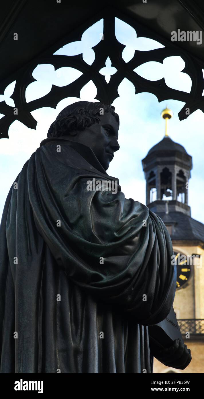 07. Januar 2022, Sachsen-Anhalt, Wittenberg Lutherstadt: Das Denkmal des Reformators Martin Luther steht auf dem Marktplatz der Wittenberg Lutherstadt vor den Türmen der Stadtkirche St. Maria. Es ist das erste Denkmal seiner Art in Deutschland, bei dem eine nicht-edle Person öffentlich mit einer freistehenden Statue geehrt wurde. Die Bronzefigur ist von Johann Gottfried Schadow, das gusseiserne Baldachin von Karl Friedrich Schinkel. Die Statue zeigt Luther barköpfig in einem Kleid, mit der offenen Bibel in seinen Händen. Es wurde 1821 errichtet. Foto: Waltraud Grubitzsch/dpa-Zentralbild/dpa Stockfoto