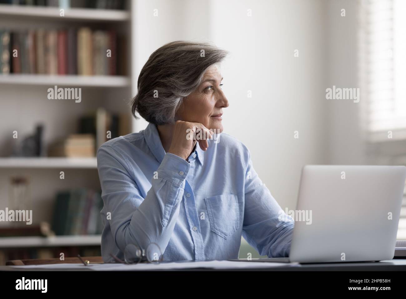 Nachdenkliche Frau mittleren Alters lenkte von der Computerarbeit ab. Stockfoto