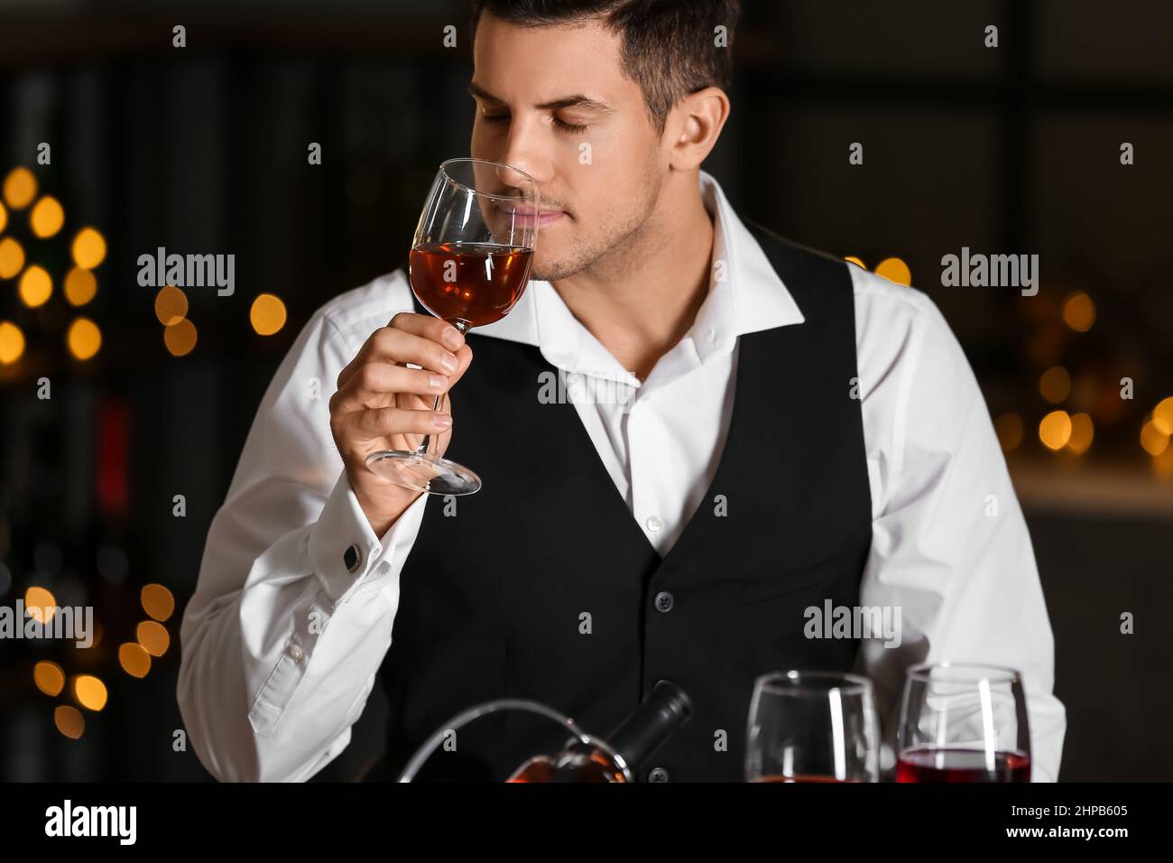 Junger männlicher Sommelier, der Weinsorten verkostet Stockfoto