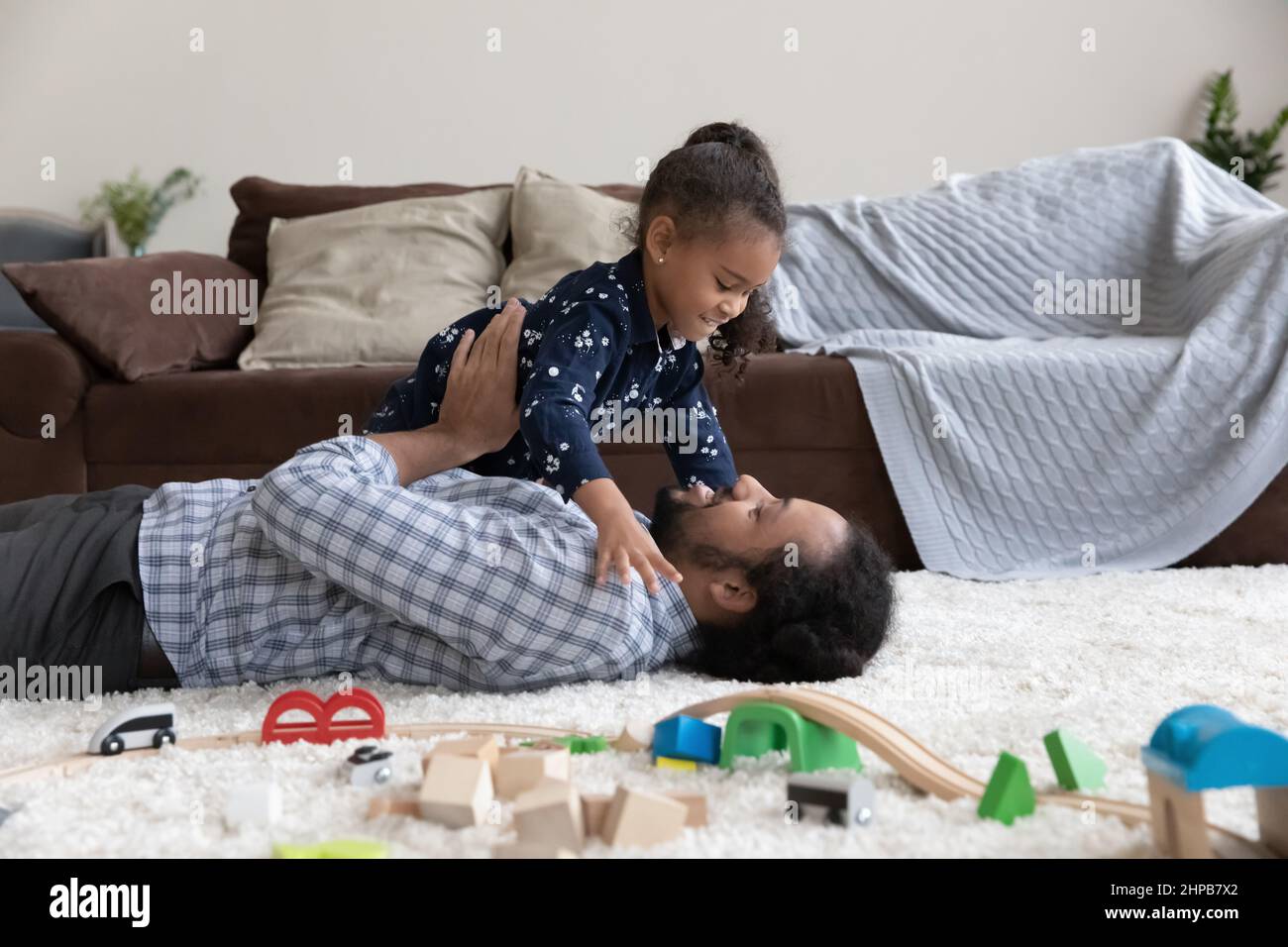 Fröhlich lachende afroamerikanische Familie, die Spaß zu Hause hat. Stockfoto