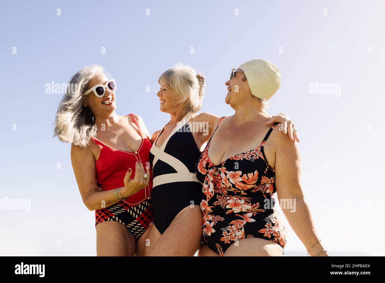 Gruppe von fröhlichen älteren Frauen, die Spaß während der Sommerferien haben. Glückliche ältere Frauen, die lachen und sich umarmen, während sie Badeanzüge tragen. Matur Stockfoto