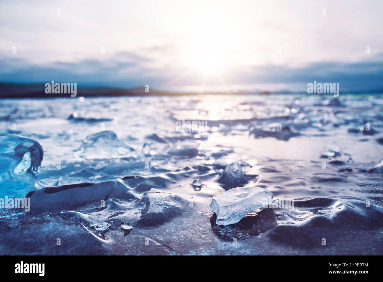 Sonnenaufgang am Baikalsee im Winter. Die Sonne reflektiert sich von der eisigen Oberfläche des Sees. Stockfoto