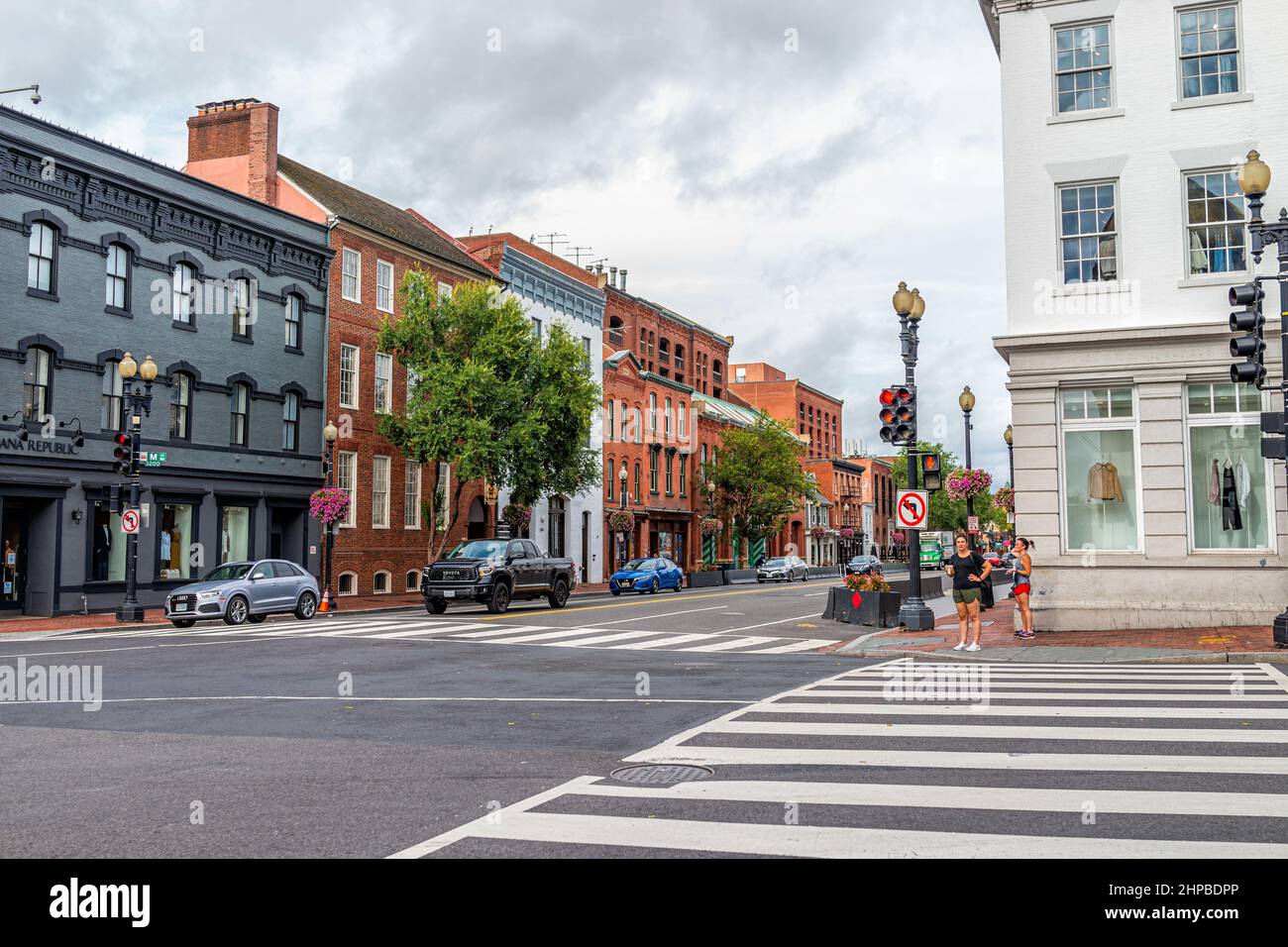 Washington DC, USA - 18. August 2021: Georgetown M Straßenlandschaft mit Geschäften Geschäfte Gebäude in der Nachbarschaft mit Menschen warten darauf, Straße wieder zu überqueren Stockfoto