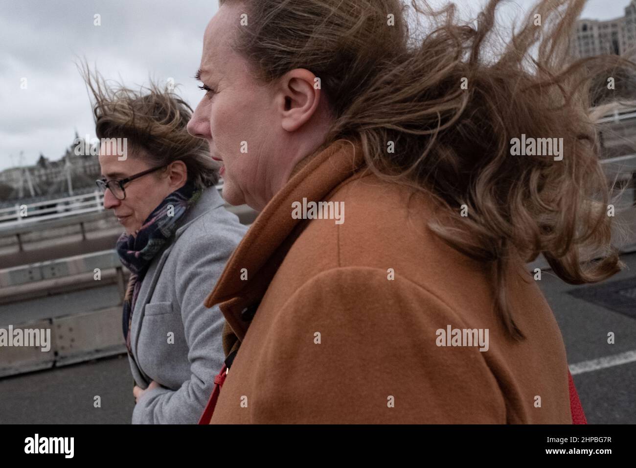 Zwei Frauen, deren Haare im Wind bläst, überqueren die Themse in London, Großbritannien Stockfoto