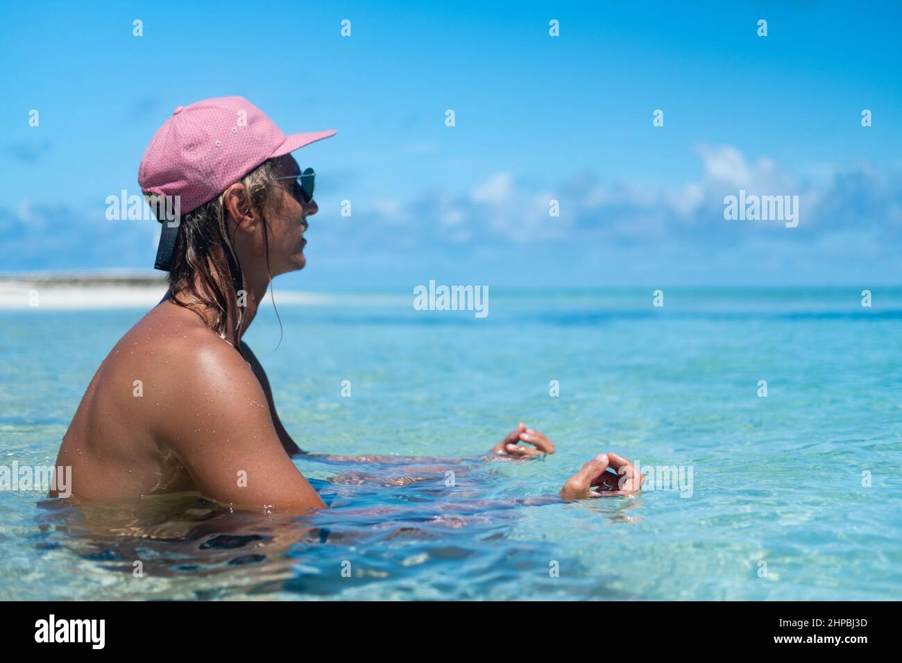 Ein Mann sitzt am Strand und hat einen tollen Blick aufs Meer. Malediven Stockfoto