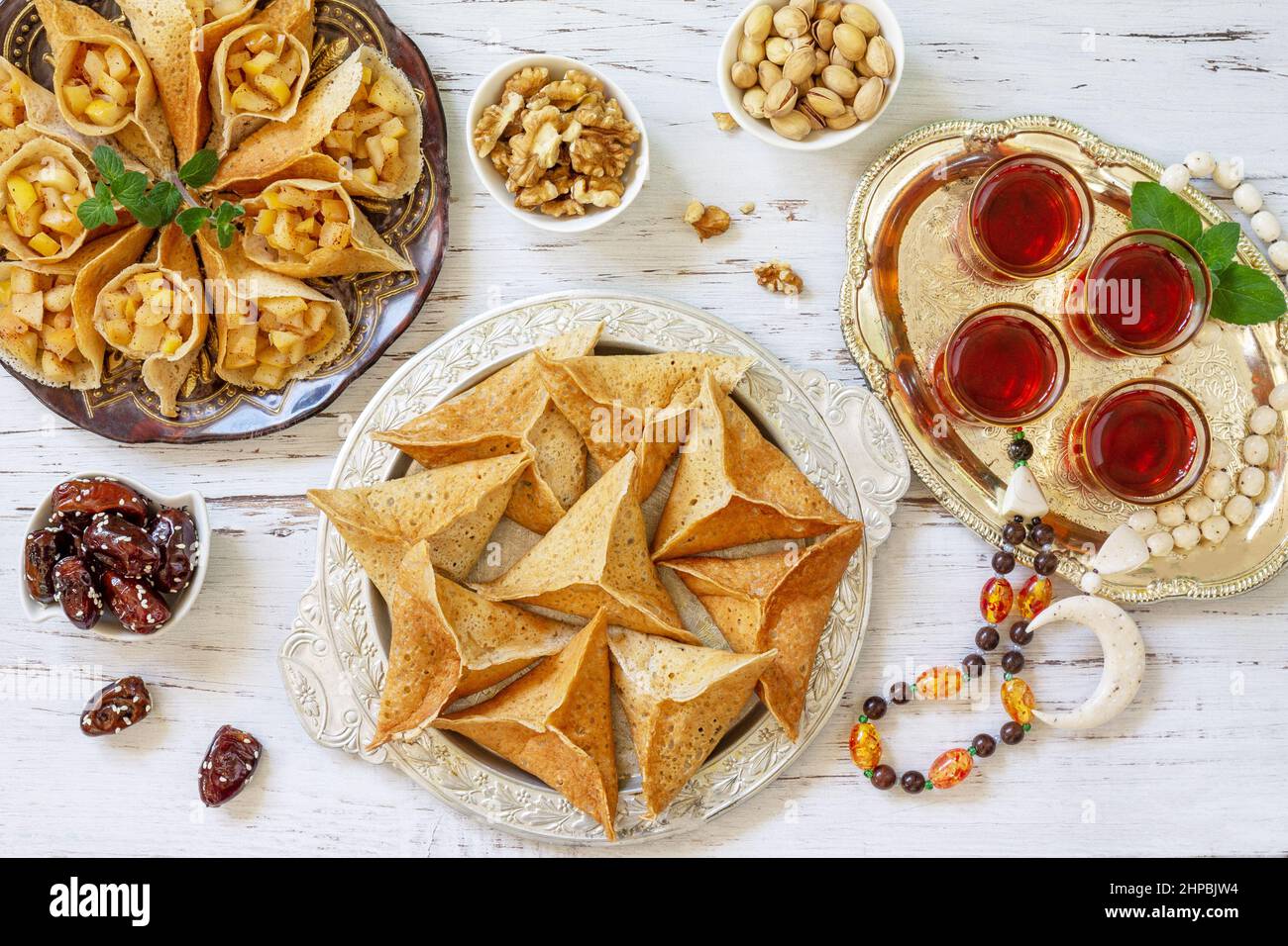 Ramadan Kareem festlich, Fasten, Halal-Essen. Ramadan-Menü: Gemischtes arabisches Pfannkuchen-Katayef und Datteln, Pistazie. Draufsicht flach liegend. Stockfoto