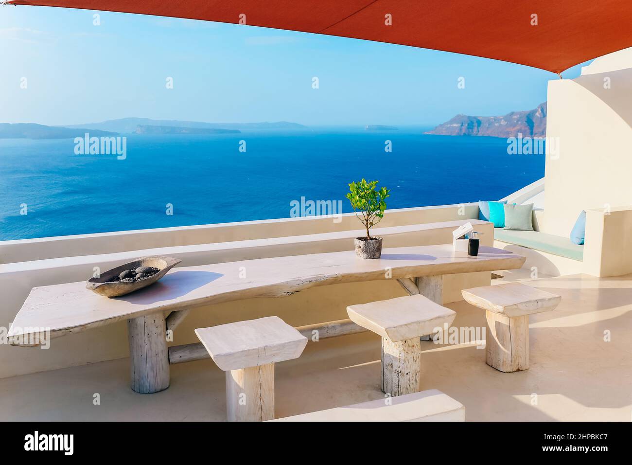 Holztisch und Hocker mit wunderschönem Meerblick auf der Terrasse in Santorini Stockfoto