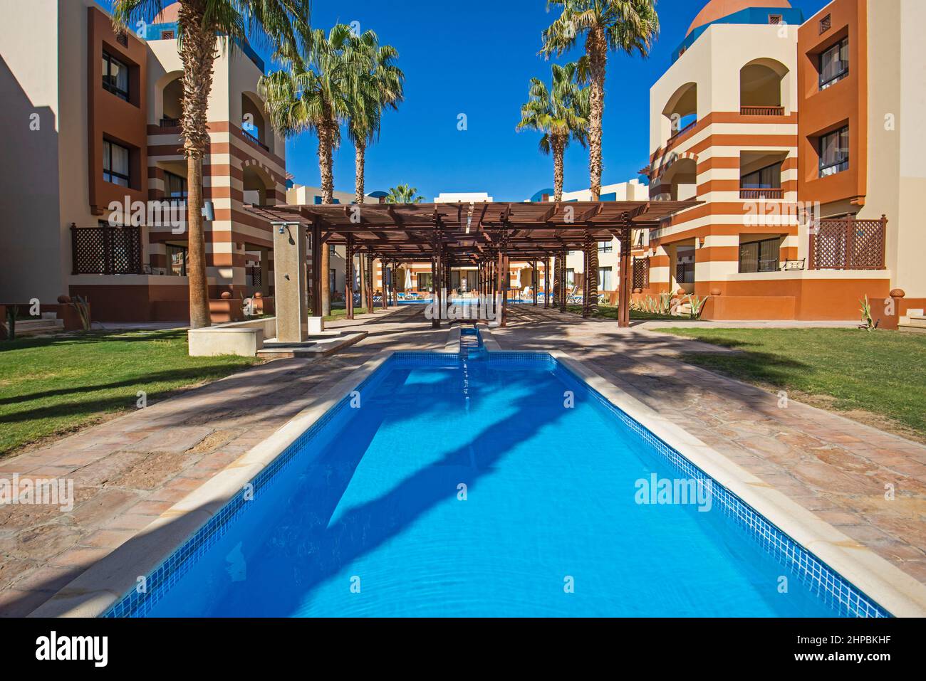 Swimmingpool mit Gebäuden in einem luxuriösen tropischen Hotelresort vor blauem Himmel Stockfoto