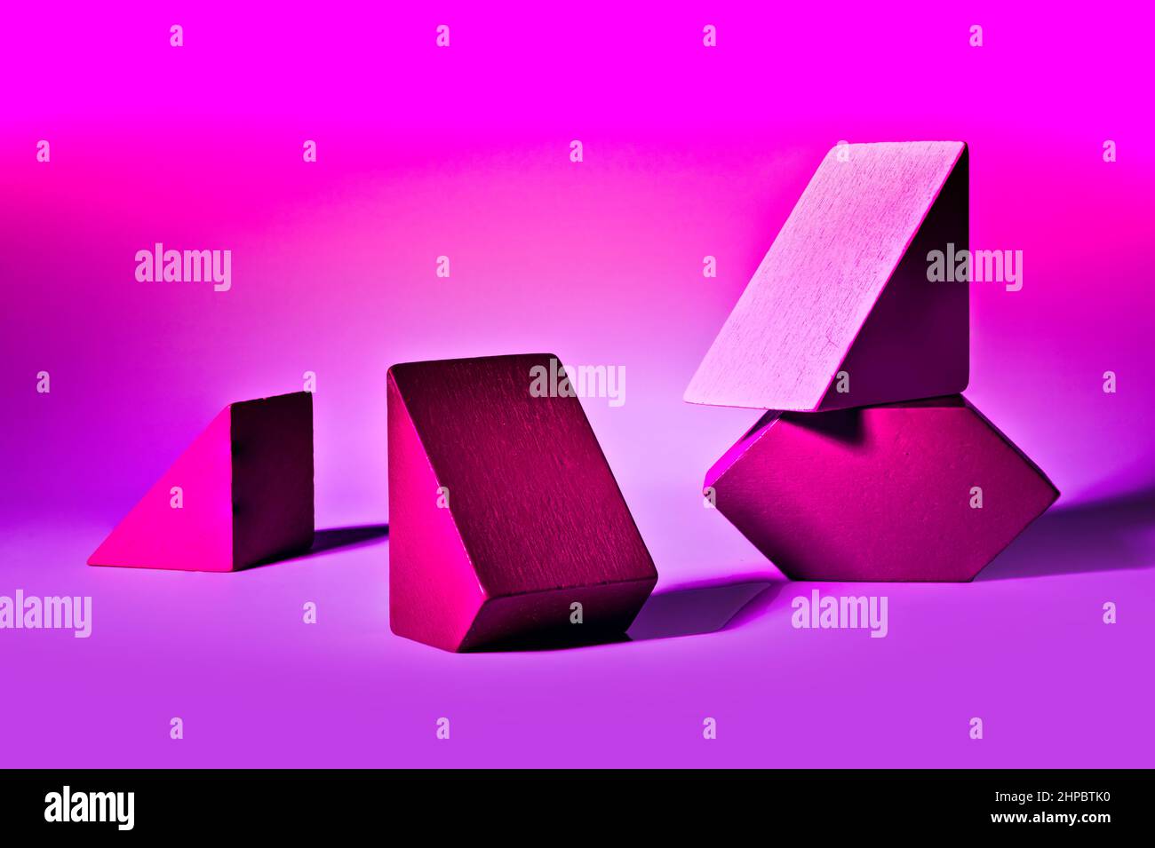 Coole Anordnung von unterschiedlich geformten geometrischen Blöcken auf rosa Hintergrund Stockfoto