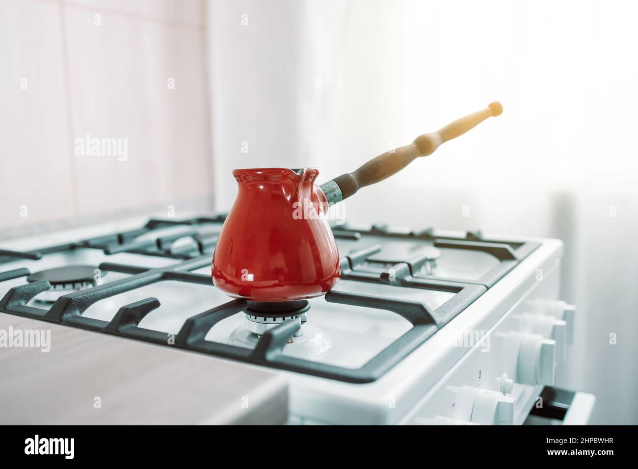 türkisches Metall-Cezve mit Griff auf Gasherd in der Küche. Morgendliche Routine Stockfoto