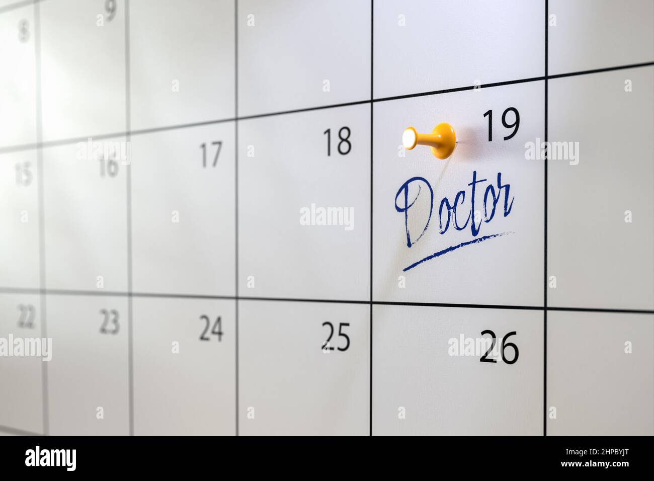 Ärzte Termin Konzept. Ein Kalender mit einem Eintrag „Doctor“ und einem Daumennack. Selektiver Fokus. Stockfoto