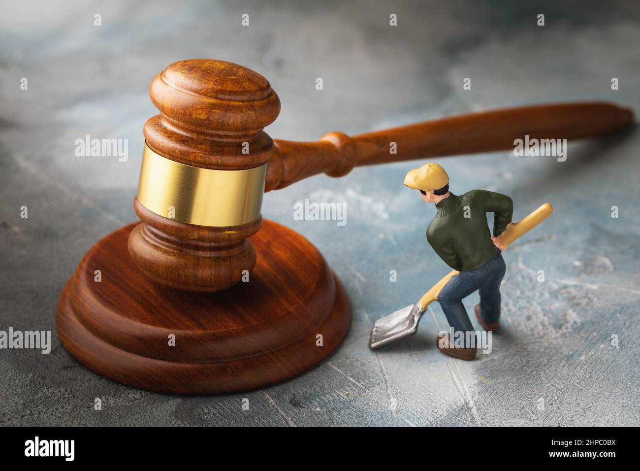 Der Gavel des Richters und eines Spielzeugmanns mit einer Plastikschaufel, ein Konzept zum Thema Wahrheitsfindung, eine Metapher, um der Wahrheit auf den Grund zu gehen Stockfoto