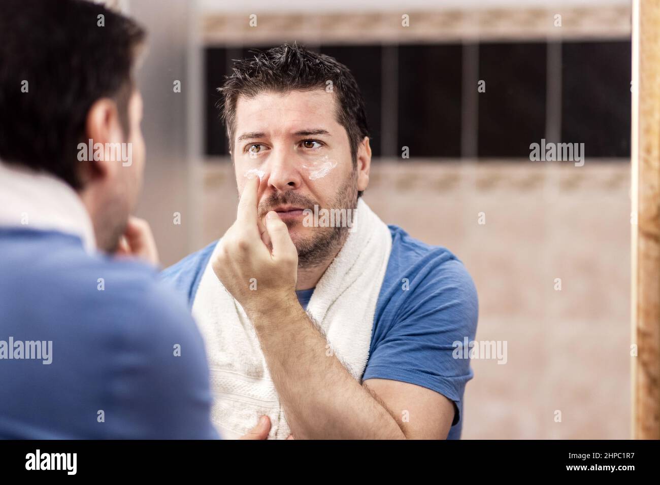 Porträt eines reifen Mannes, der Anti-Aging-Creme unter den Augen auftragend Stockfoto