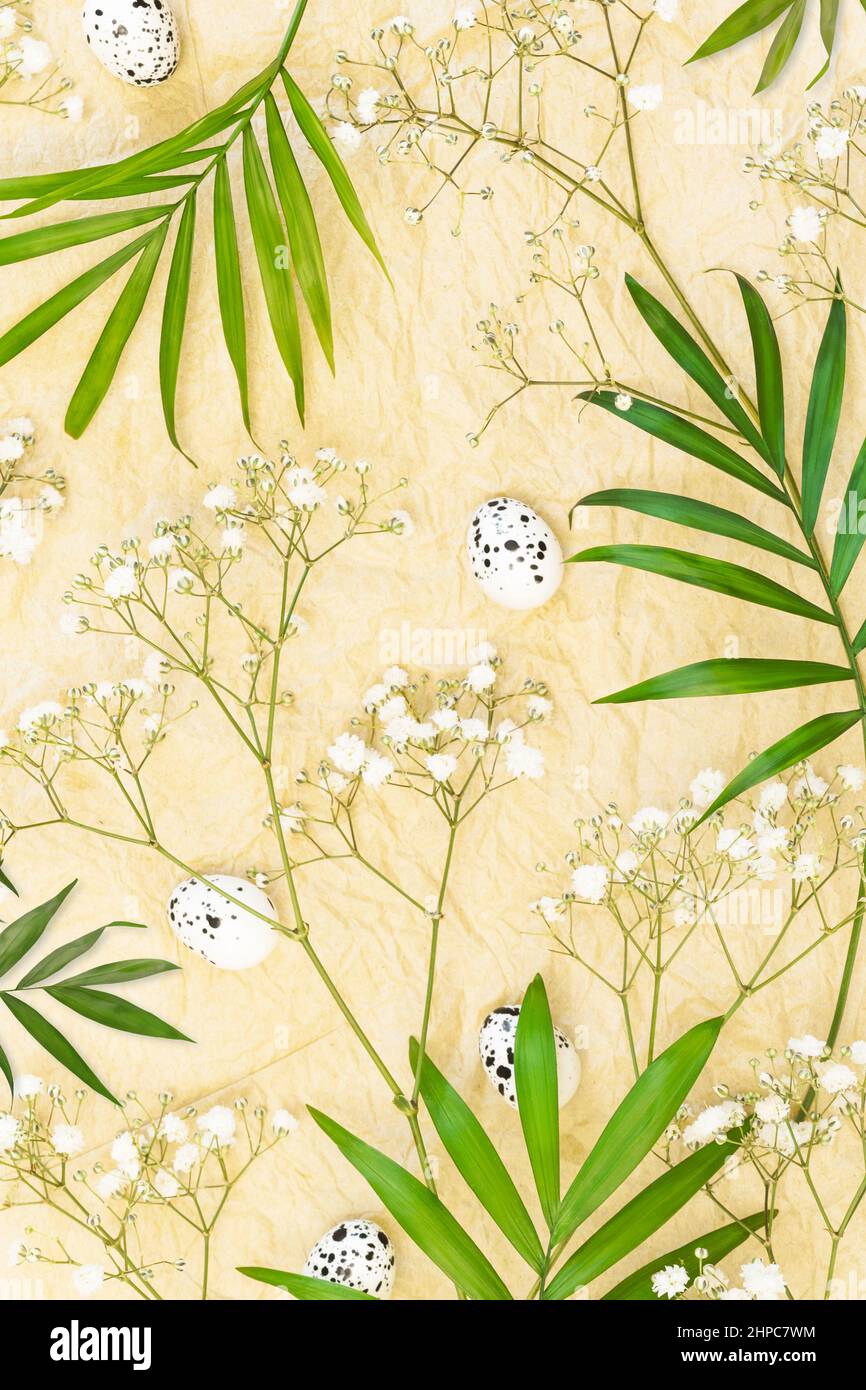 Osterferien Hintergrund. Frühlingsblumen mit Palmblättern, Eiern und weißen Gipsophila-Blüten auf einem handwerklich zerknitterten Papier Stockfoto