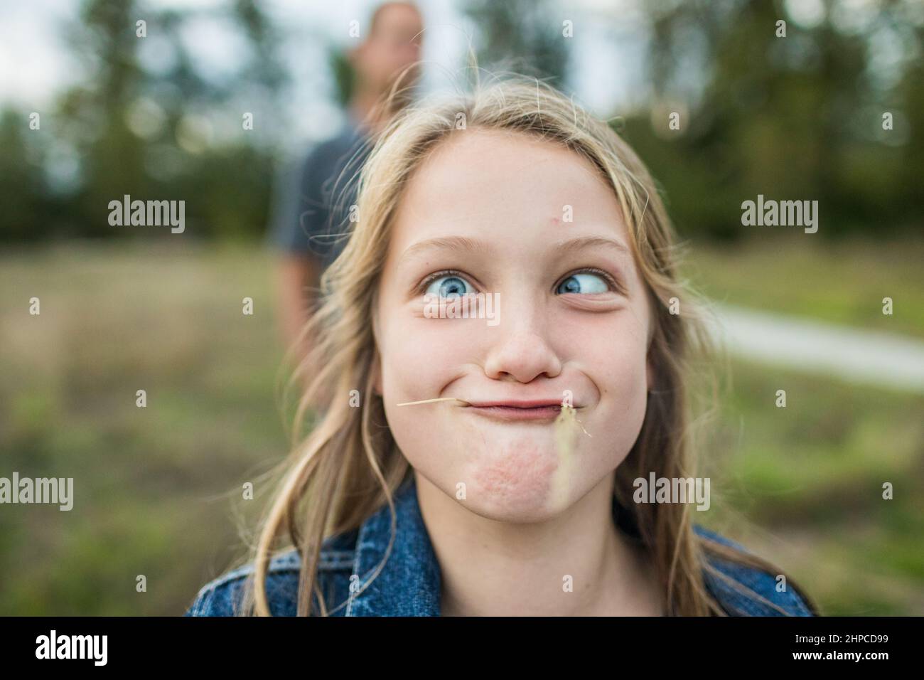 Junges Mädchen macht Schwellergesicht, verrückte Augen, Gras im Mund. Stockfoto