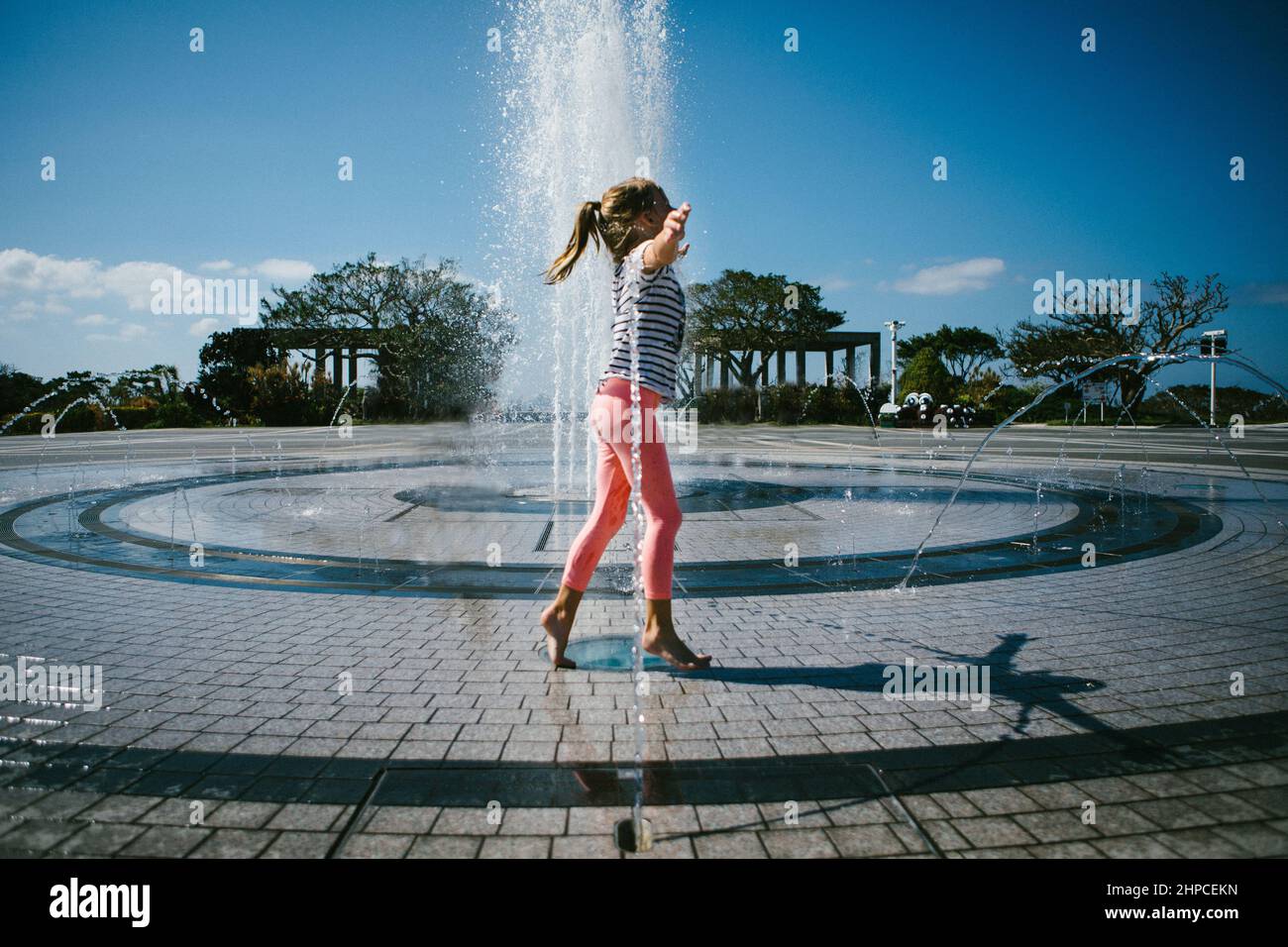 Mädchen spielt in Wasserbrunnen am heißen Sommertag Stockfoto