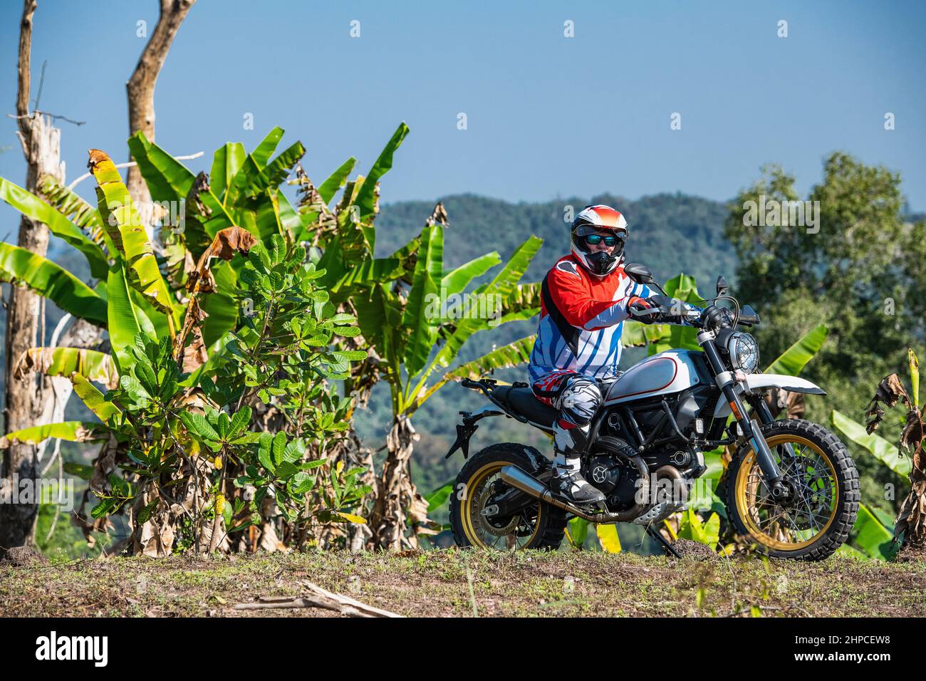 Mann mit seinem Scrambler-Motorrad auf unwegsamem Gelände in Thailand Stockfoto