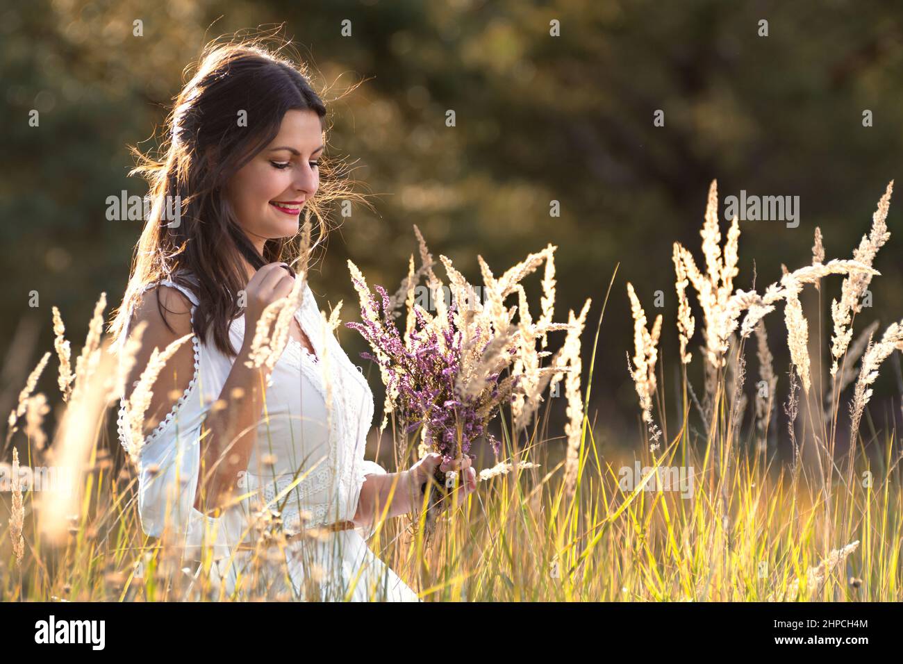 Junge hübsche Frau mit Blumenstrauß im Heidekraut. Stockfoto