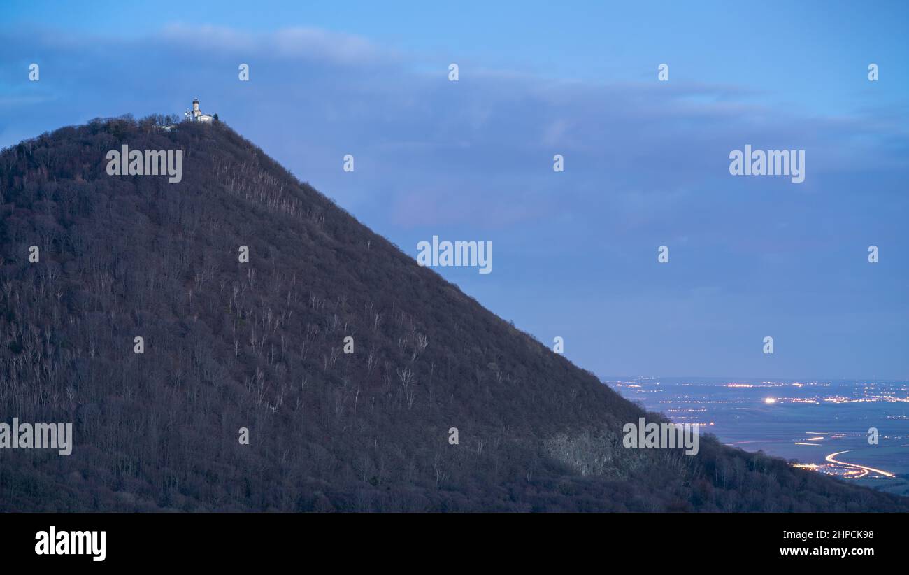 Nachtansicht des Berges Milešovka (Donnersberg) in der Tschechischen republik, mit einem meteorologischen Observatorium und bewaldeten Hängen. Von Zvon Hill. Stockfoto