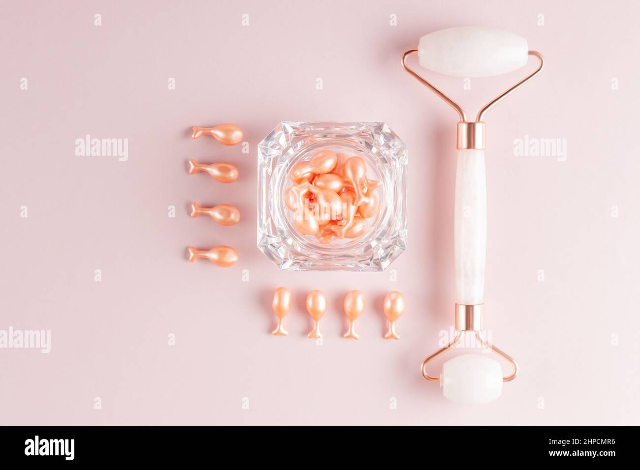 Pink Quarts Gesichtswalze und Serumkapseln mit Einzeldosis in einer Packung. Gesichtsmassage. Behandlung von Naturkosmetik. Monochromatischer Look, Knollenkonzept Stockfoto