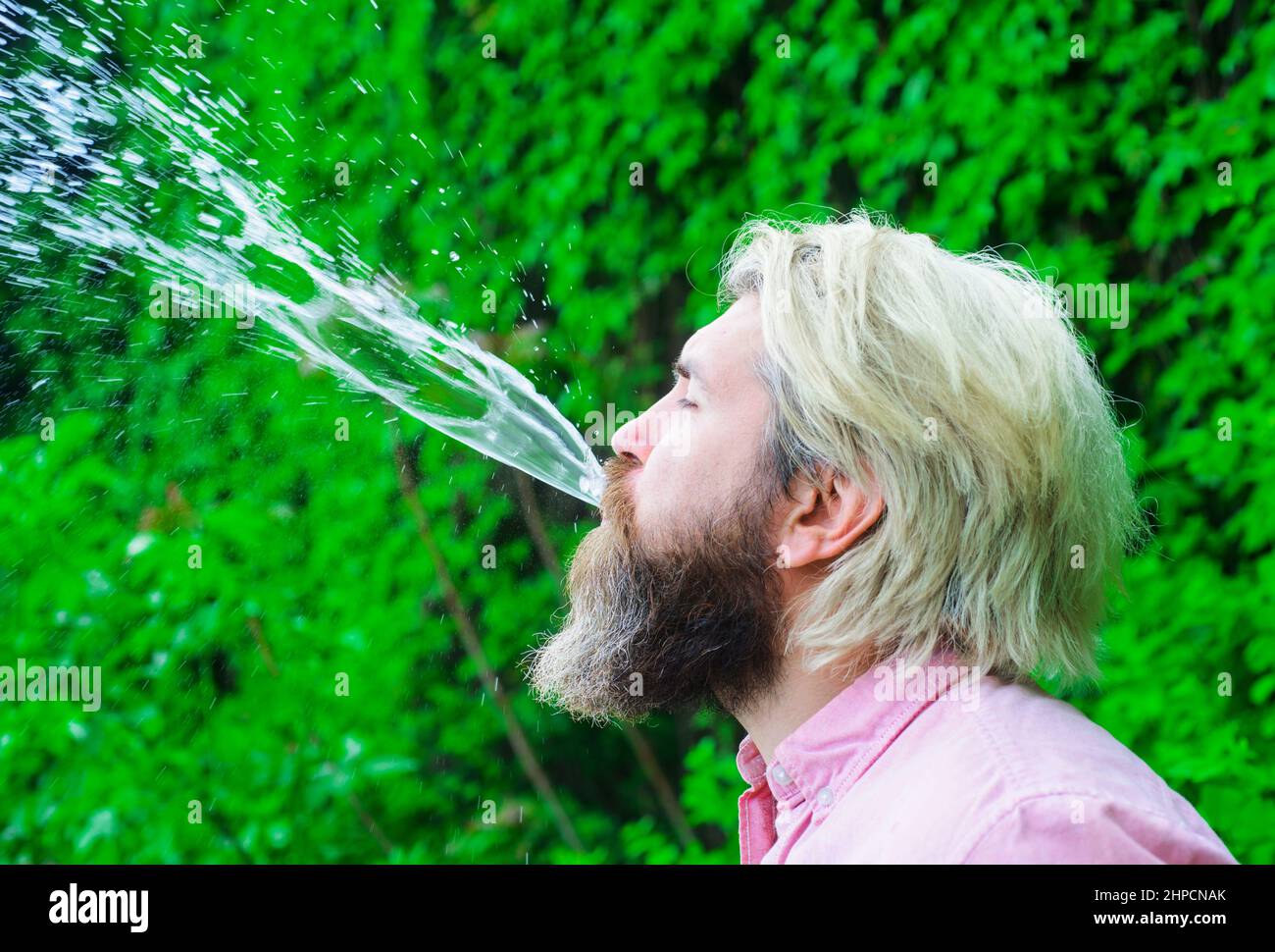 Der Mensch spuckt Wasser. Gesunder Lebensstil. Trinkwasser. Hydratation und Drink Konzept. Stockfoto