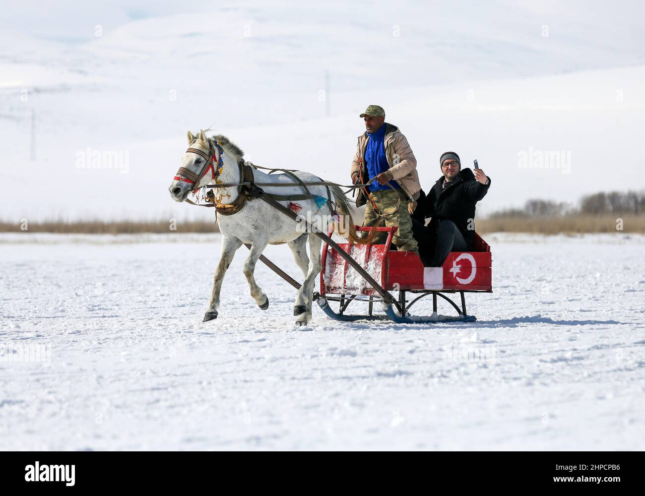 Kars, Istanbul, Türkei. 19th. Februar 2022. Der Cildir-See im Nordosten der Türkei zieht das ganze Jahr über und vor allem im Winter Touristen an.der Cildir-See liegt zwischen den türkischen Provinzen Kars und Ardahan in der Region Ostanatolien und ist ein beliebter Ort für den Wintertourismus in der Türkei sowohl für einheimische als auch für ausländische Touristen. Von Pferden gezogene Schlitten reiten Touristen über den zugefrorenen See. Andere Touristen schwelgen beim Eisfischen. (Bild: © Serkan Senturk/ZUMA Press Wire) Stockfoto