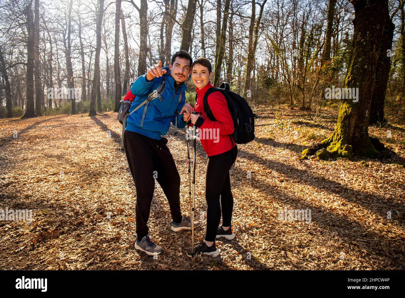 Ein junges lächelndes Paar wandert im Wald. Der Mann weist seiner Freundin den richtigen Weg. Reise- und Outdoor-Life-Konzept. Stockfoto