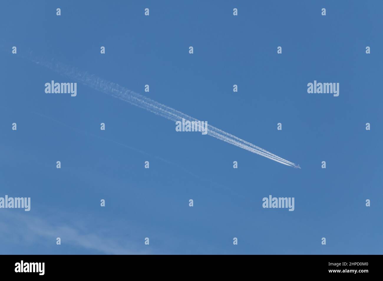 Contrails - ein fliegendes Transportflugzeug mit weißen Kondensstreifen am blauen Himmel Stockfoto