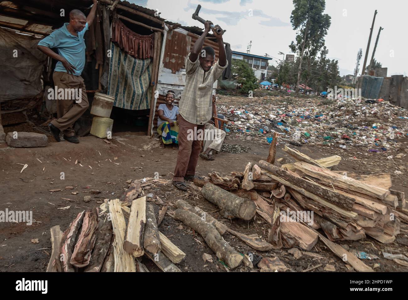 Ein Mann schneidet in den Slums von Kibera in Nairobi Brennholz auf den Straßen. Im Kibera Slum, dem berüchtigten Zuhause, wo das Leben immer schwierig und klägig zu sein scheint Stockfoto