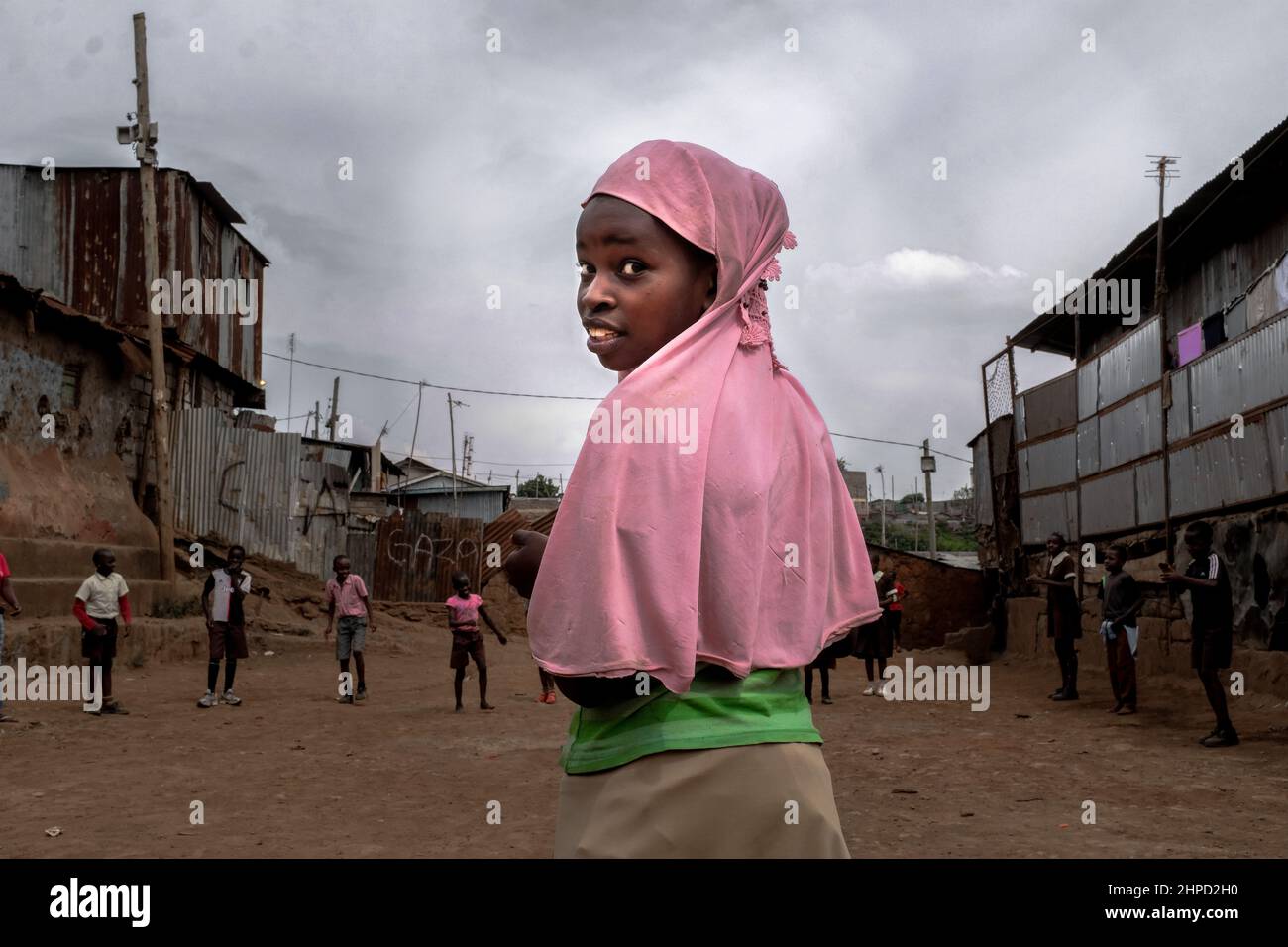KENIA, Nairobi, Kibera Slum, muslimisches Mädchen, das während der Schulferien auf der Straße spielt. Im Kibera Slum, der berüchtigten Heimat, in der das Leben immer scheint Stockfoto
