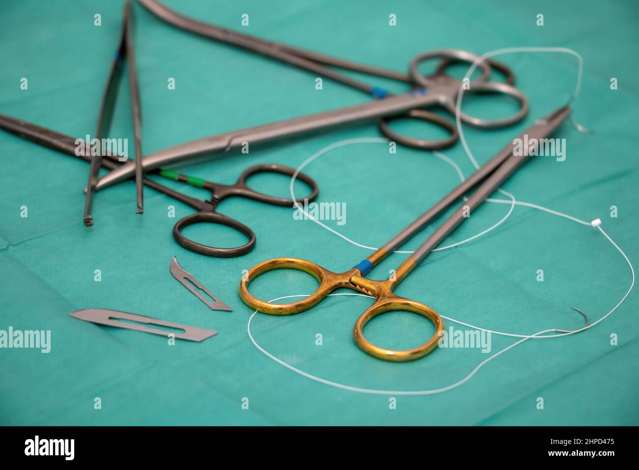 Sterilisiertes Operationsinstrument auf grünem Stoffhintergrund. Chirurg Arzt Edelstahlwerkzeug, Zangenzange, Nadelhalter oder Treiber, Schere, Klinge, Sutu Stockfoto