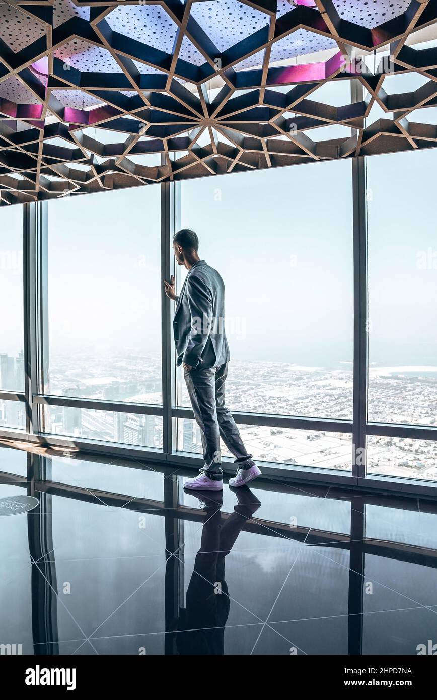 Junger Mann, der Dubai vom Wolkenkratzer Burj Khalifa aus erkundet. Stockfoto