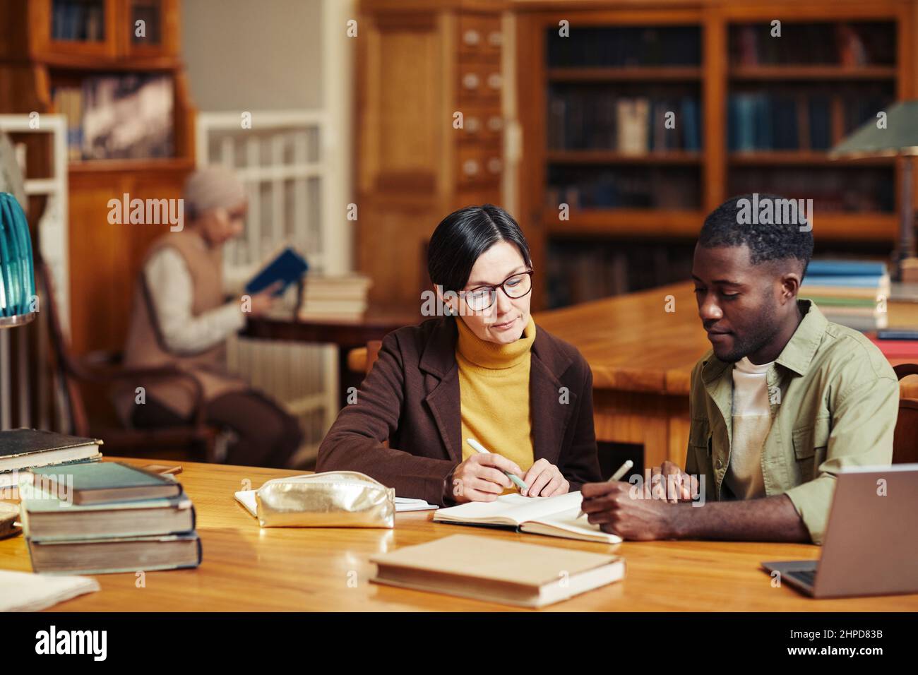 Porträt einer Professorin, die eine schwarze Studentin in der klassischen Bibliothek unterrichtet Stockfoto