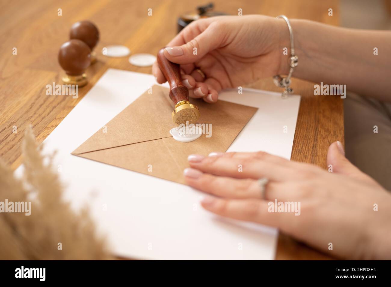 Zugeschnittenes Foto von Frau Hände Herstellung Zertifikat Geschenk Umschlag Handwerk, Holz Schreibtisch, setzen Versiegelung Wachs drucken. Stempeln Stockfoto