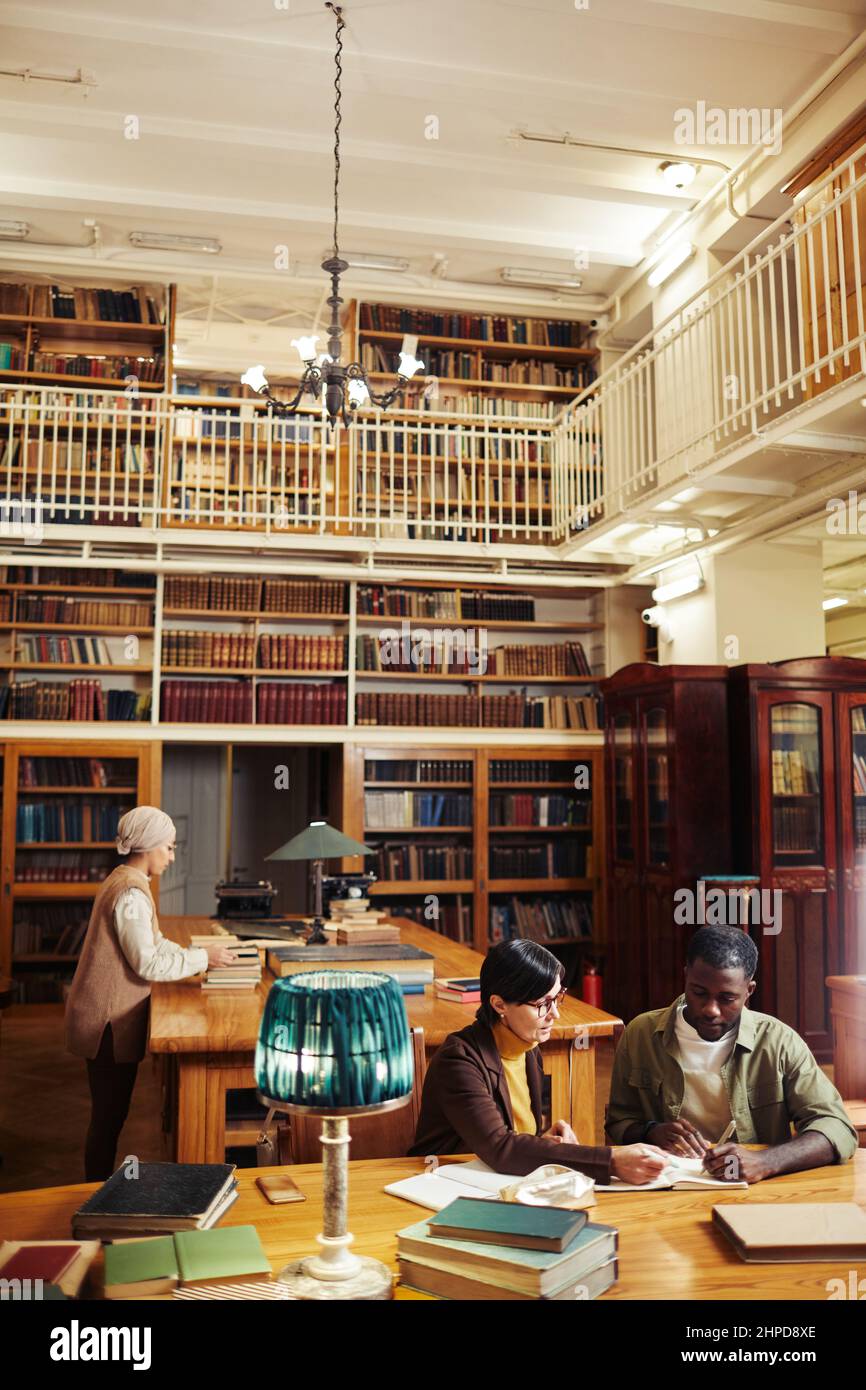 Vertikaler Weitwinkel bei verschiedenen Gruppe von Menschen, die in klassischen Bibliothek Interieur an der Hochschule studieren, kopieren Raum Stockfoto