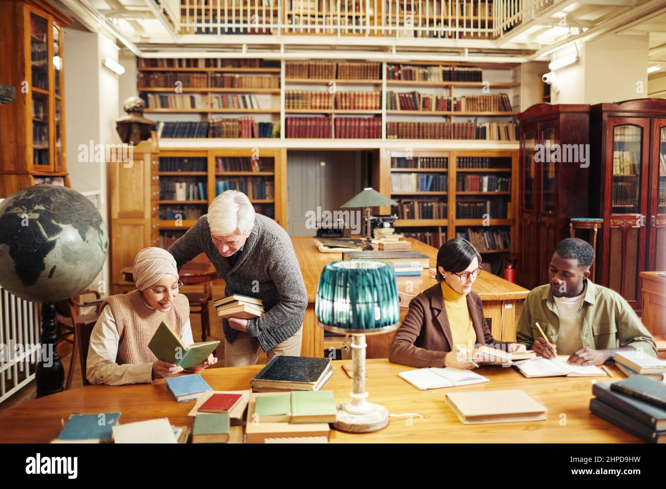 Warm getönte Porträt von verschiedenen Gruppe von Menschen, die am Tisch in der klassischen College-Bibliothek studieren, kopieren Raum Stockfoto